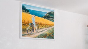 A room with a sofa, a glass table, and a framed painting of a landscape. - Hotel Morri's (Rimini)