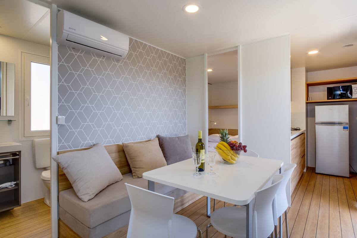 A modern kitchen with a white refrigerator, a microwave, and a wooden shelf.