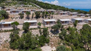 Eine Reihe moderner, eingeschossiger Blockhütten mit großen Fenstern, gelegen an einem felsigen Hang mit Blick auf das Meer.