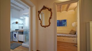 Un corridoio che porta a una camera da letto con un letto, una cassettiera e un quadro appeso al muro.