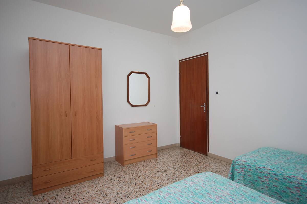 A bedroom with a wardrobe, a dresser, a mirror, and a door.