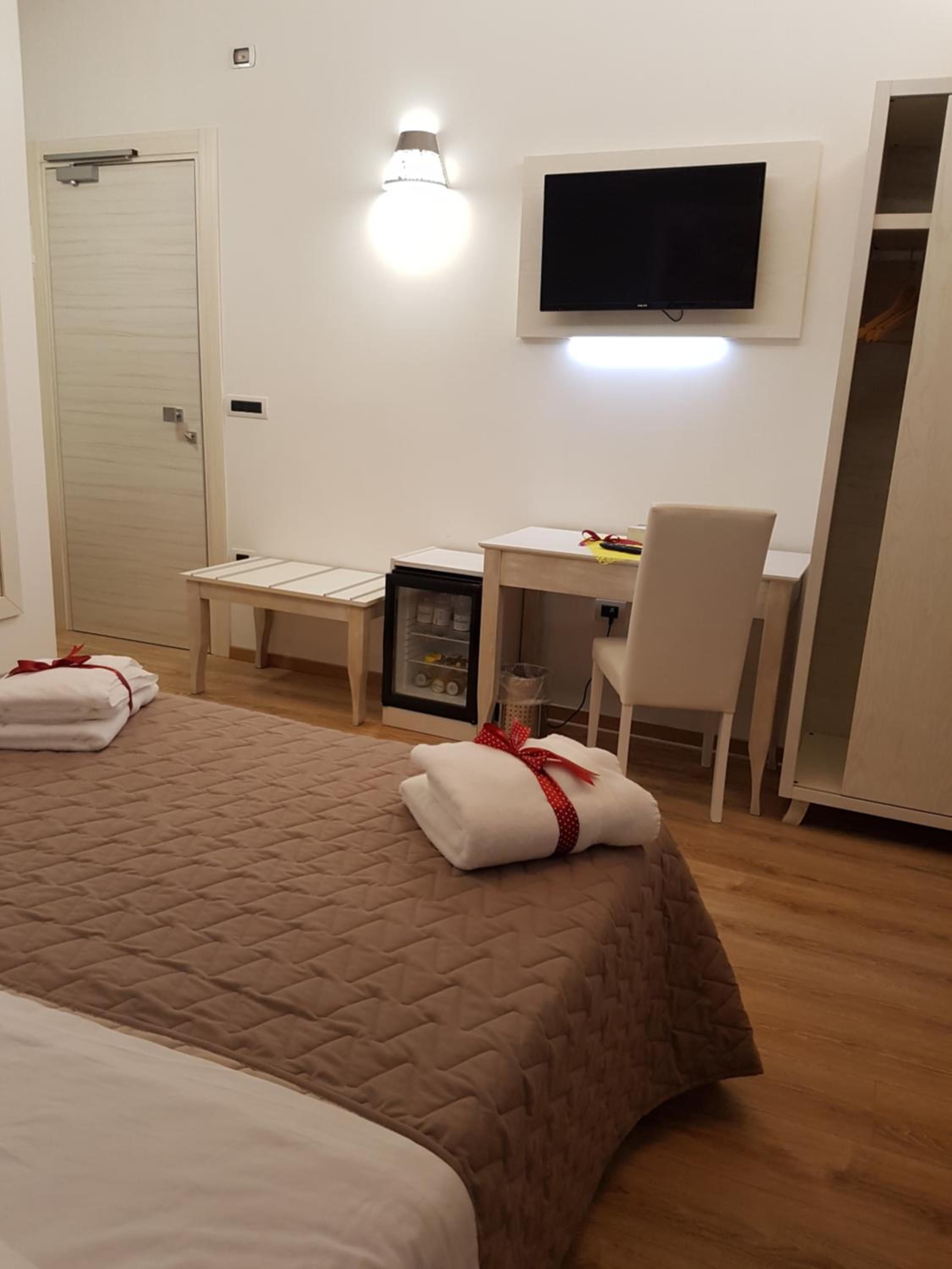 Une chambre d’hôtel équipée d’un lit, d’un bureau, d’une chaise, d’une télévision et d’un mini-bar.