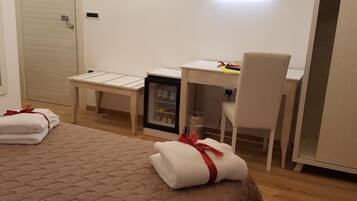 Une chambre d’hôtel équipée d’un lit, d’un bureau, d’une chaise, d’une télévision et d’un mini-bar.