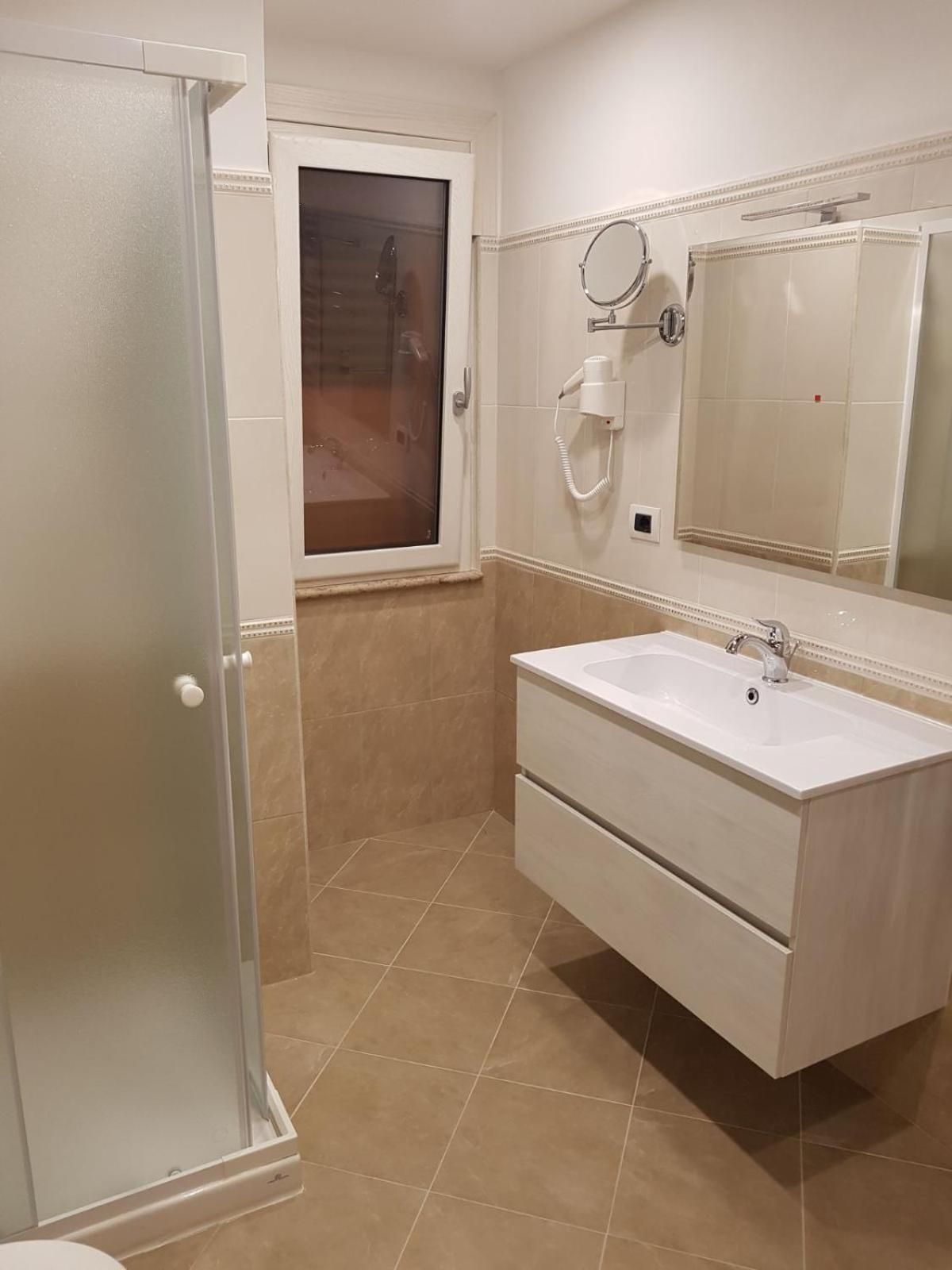 Een badkamer met een wit wastafelmeubel, een spiegel en een douche.