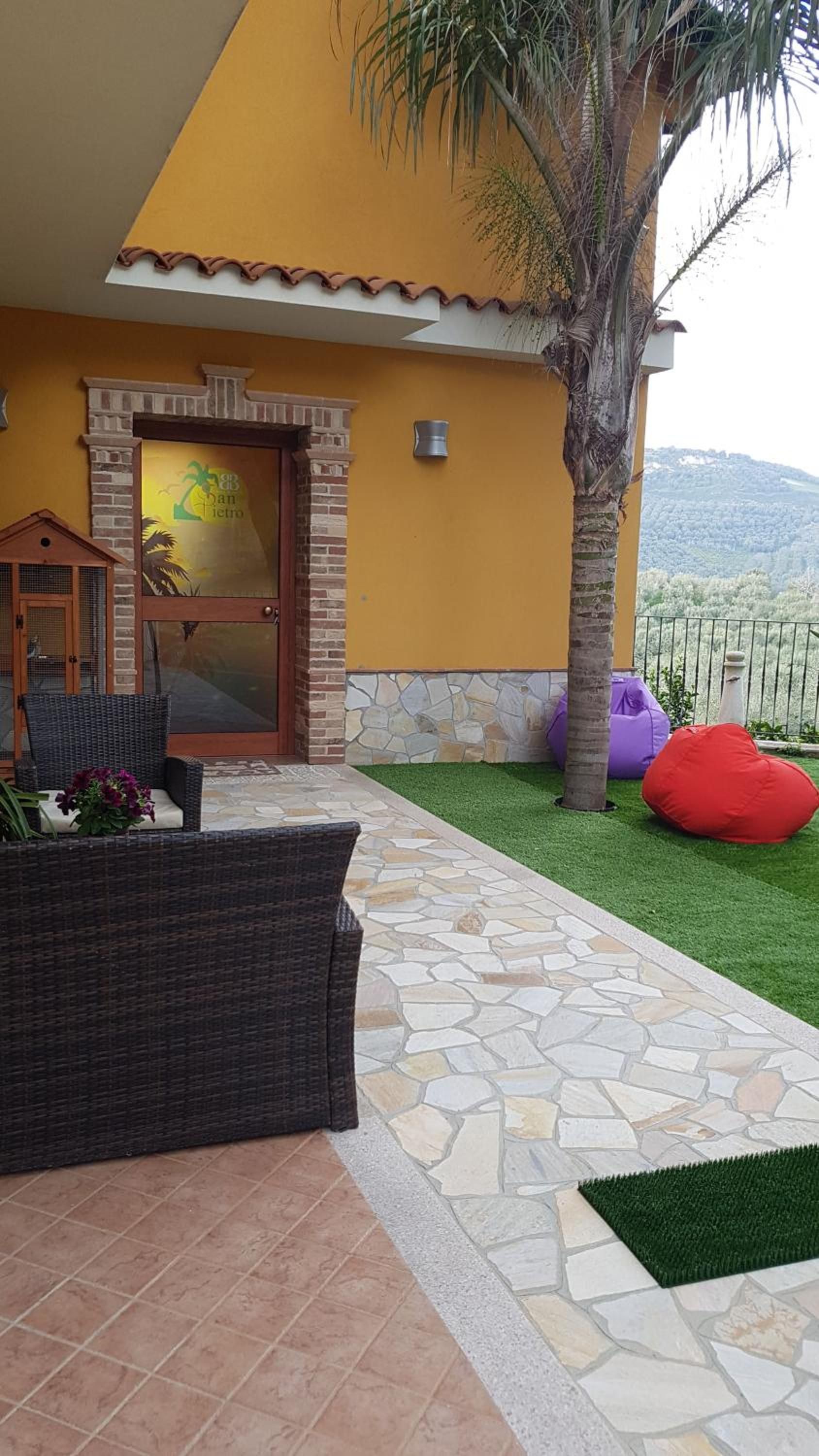 A house with a stone patio, a glass door, and a view of the landscape.