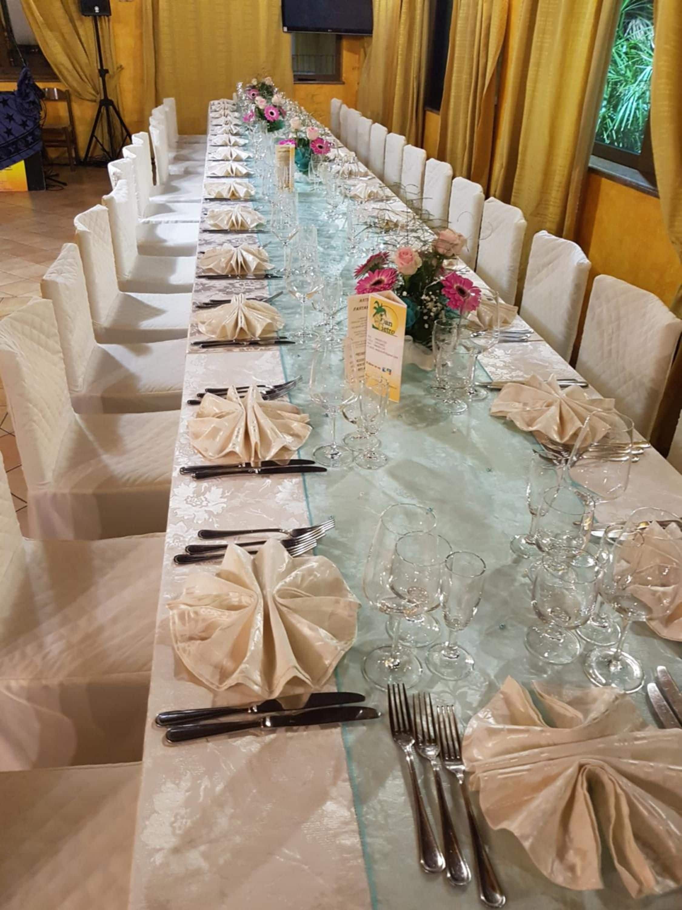 A long banquet table set with folded napkins, cutlery, and glassware, likely prepared for a formal event.