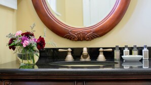 A bathroom with a sink, mirror, and toiletries. - Athenaeum Hotel (Mayville)