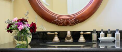 A bathroom with a sink, mirror, and toiletries.