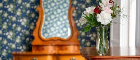 A wooden dresser with a mirror and a vase of flowers.