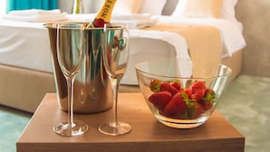 Ein Zimmer mit einem Bett, einem Nachttisch mit einer Champagnerflasche, zwei Gläsern und einer Schale Erdbeeren.