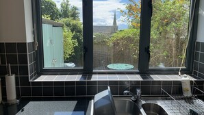 Eine Küche mit einem großen Fenster, einem Spülbecken und einem Geschirrgestell.