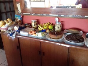 Un buffet proposant une variété d’aliments, notamment du pain, des fruits et des desserts.