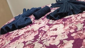 Habitación de hotel con cama, televisor montado en la pared y cabecera con estampado floral.