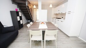 Eine moderne Küche mit weißen Schränken, einem Holzespeisebereich und einer Treppe.