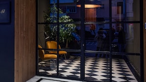 L’entrée d’un hôtel avec un sol à carreaux, un mur en bois et une porte en verre.