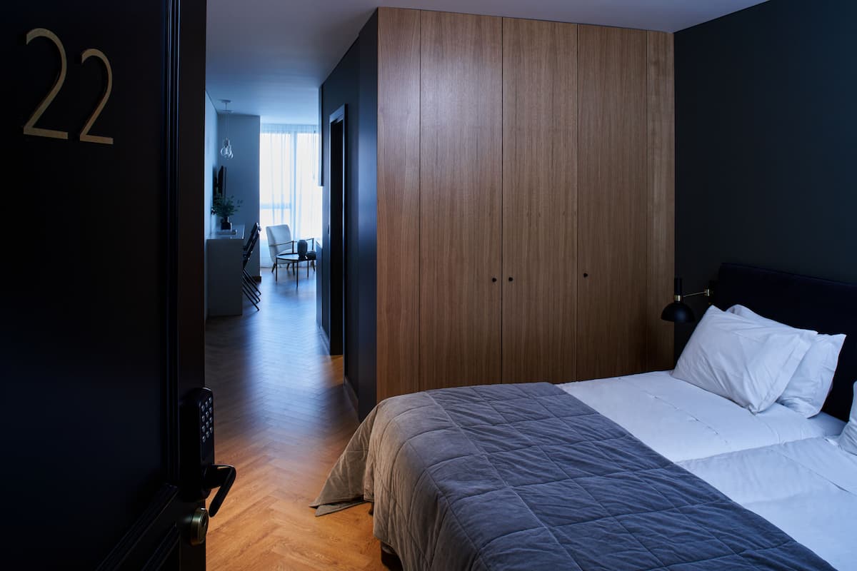 A bedroom with a large bed, wooden wardrobe, and a visible door number '22'.