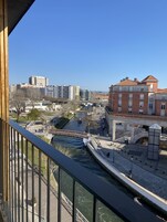 Vista junto al río con un puente, edificios y una estructura moderna.