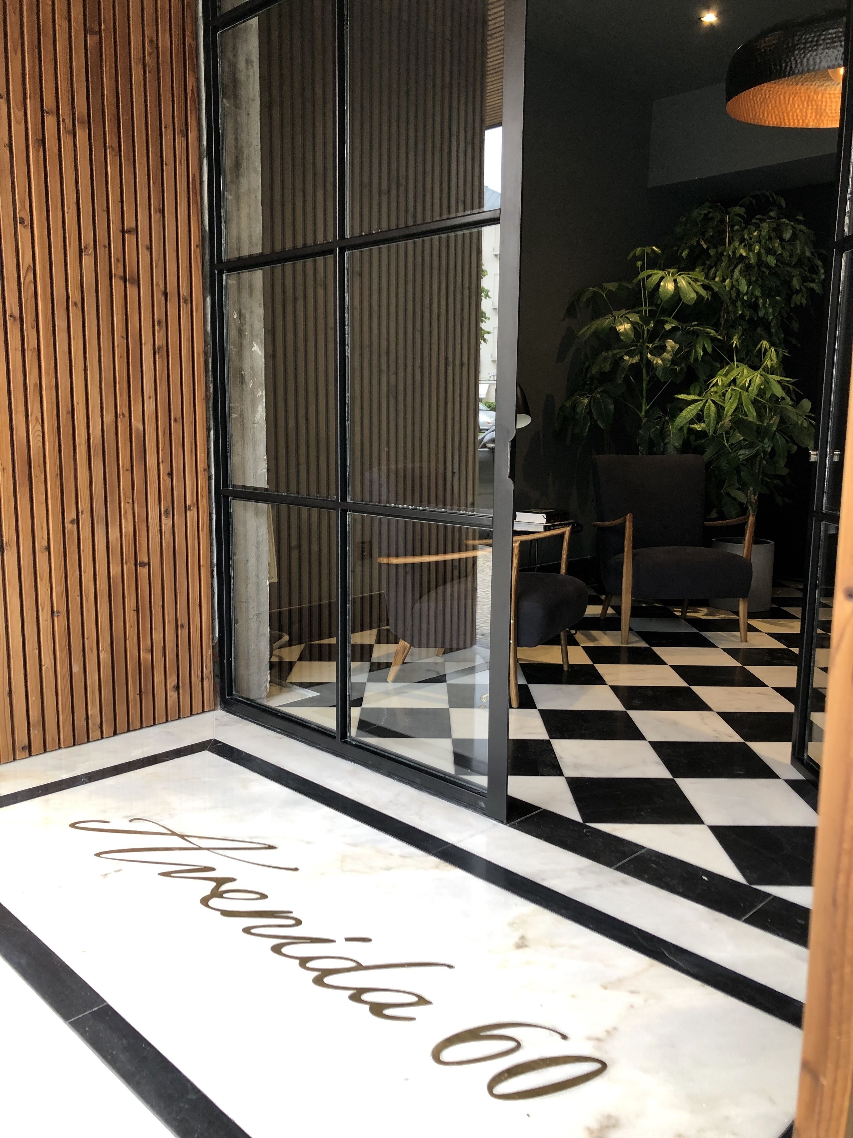 Un interior moderno con piso a cuadros, pared de paneles de madera y puerta de vidrio con un letrero que dice 'Hotel 60'.