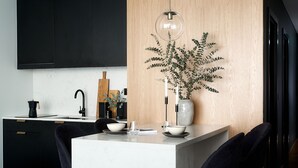 Une cuisine moderne dotée d’un îlot central, de meubles de couleur noire et d’un mur d’accent en bois.