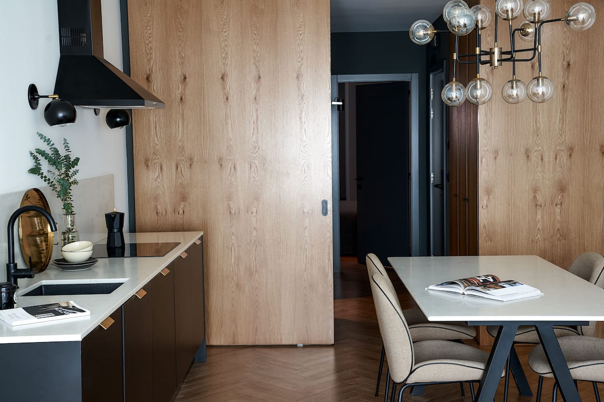 A modern kitchen with a wooden cabinet, a white countertop, and a black range hood.