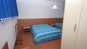 A bedroom with a bed, bedside tables, a wardrobe, and a ceiling light. - Villa Isolina (Lignano Sabbiadoro)