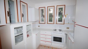 A compact kitchen with white cabinets, a built-in oven, and a sink. - Villa Isolina (Lignano Sabbiadoro)