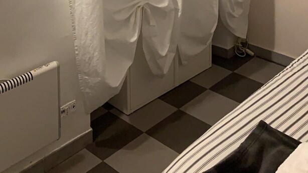 A room with a checkered floor, a bed with a striped bedspread, and a white curtain with a bow tied at the bottom. - Bed2Go (Turin)