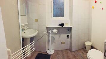 Une petite salle de bain avec un lavabo, des toilettes et une fenêtre.