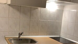 A kitchen with a stainless steel sink, wooden countertop, and light grey cabinets. - Bed2Go (Turin)