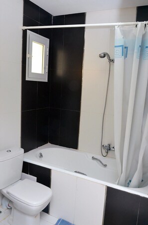 Un baño con bañera, inodoro y ventana.