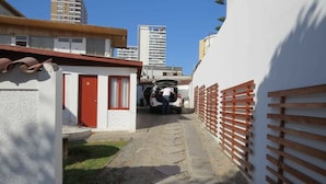 A narrow alleyway with a parked car and a small building with a red door. - Pälm Hostal (Iquique)