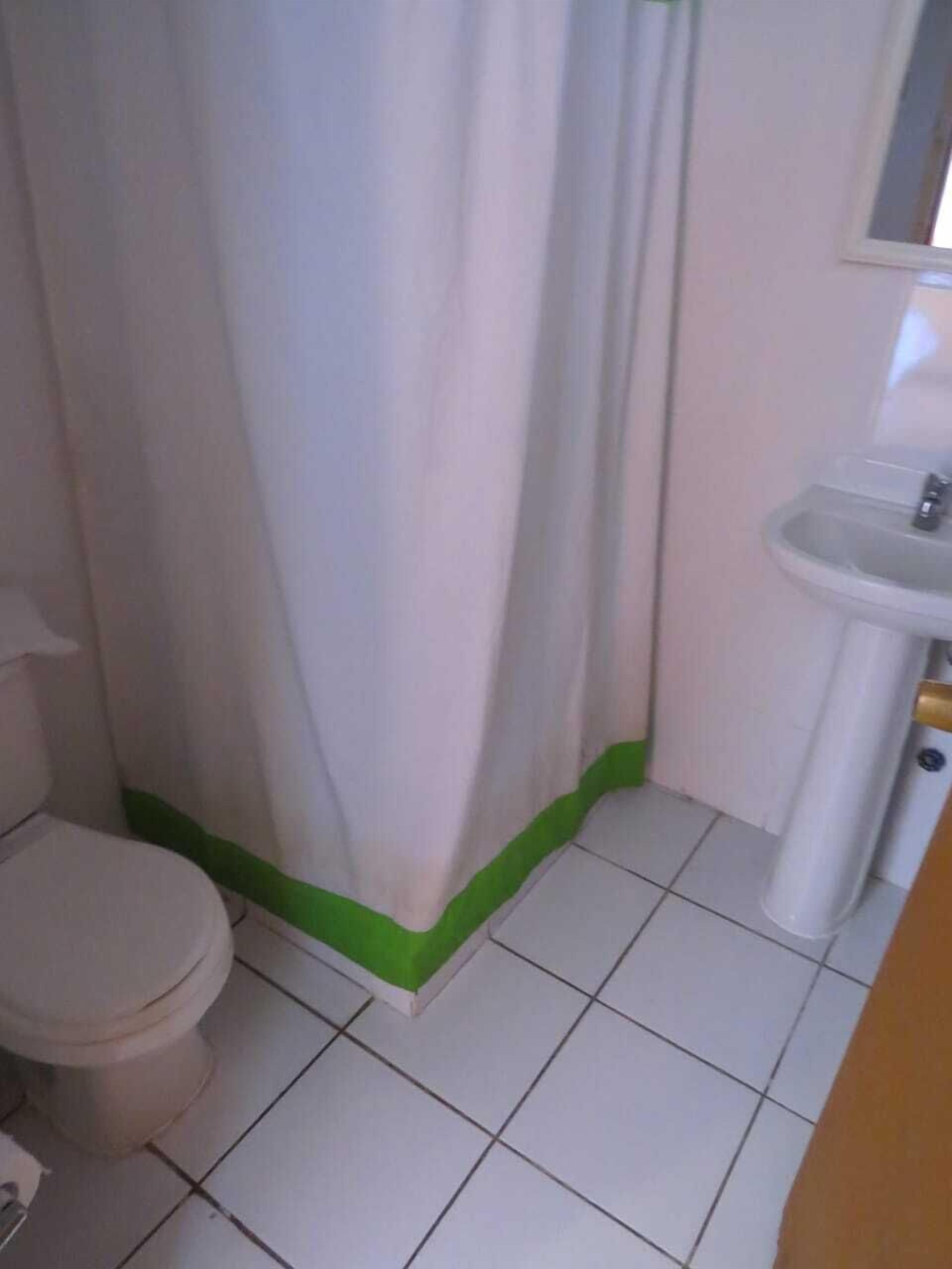 Un baño pequeño con inodoro, lavamanos y cortina de ducha.