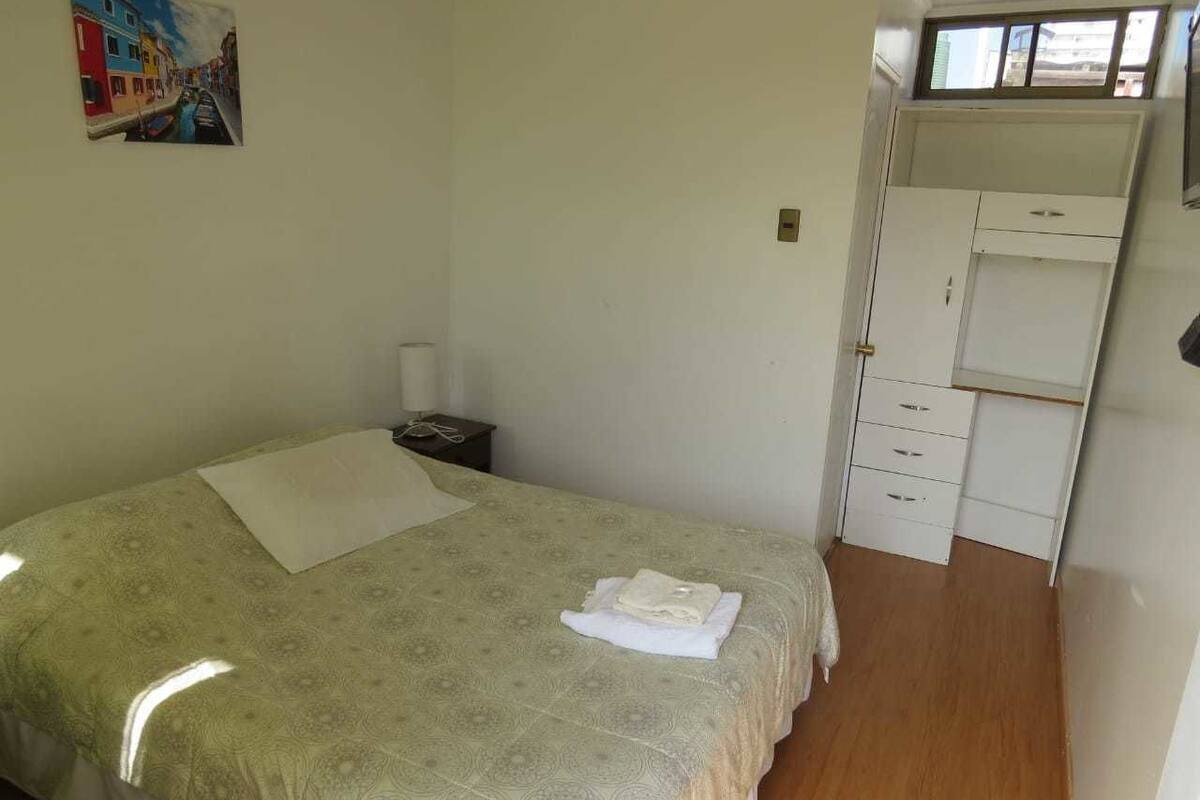 Ein Schlafzimmer mit einem Bett, einem Nachttisch, einem Schreibtisch und einem Kleiderschrank.