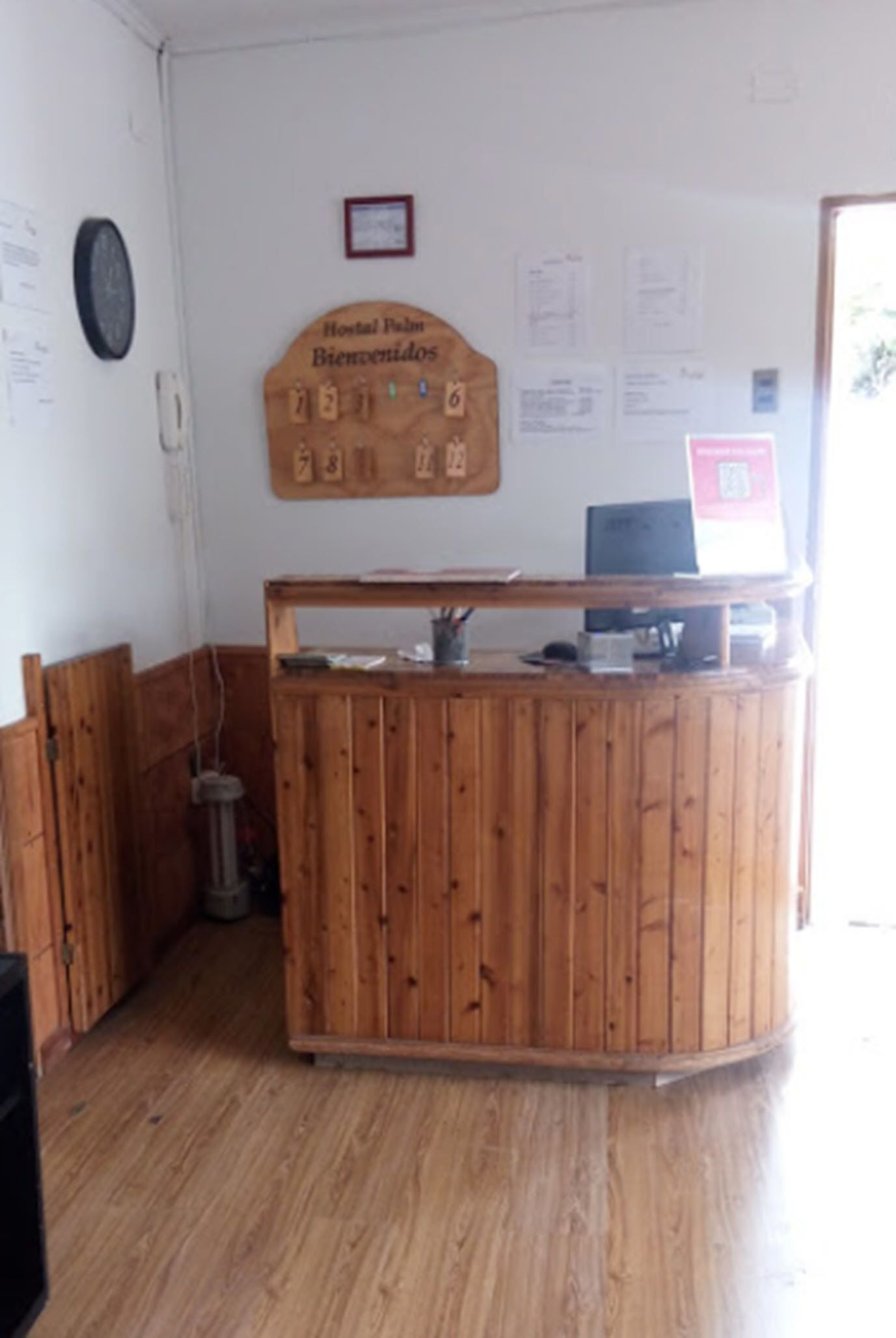 A reception desk with a wooden design, a clock on the wall, and various notices.