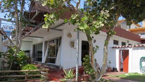A house with a porch, potted plants, and a visible door. - Pälm Hostal (Iquique)