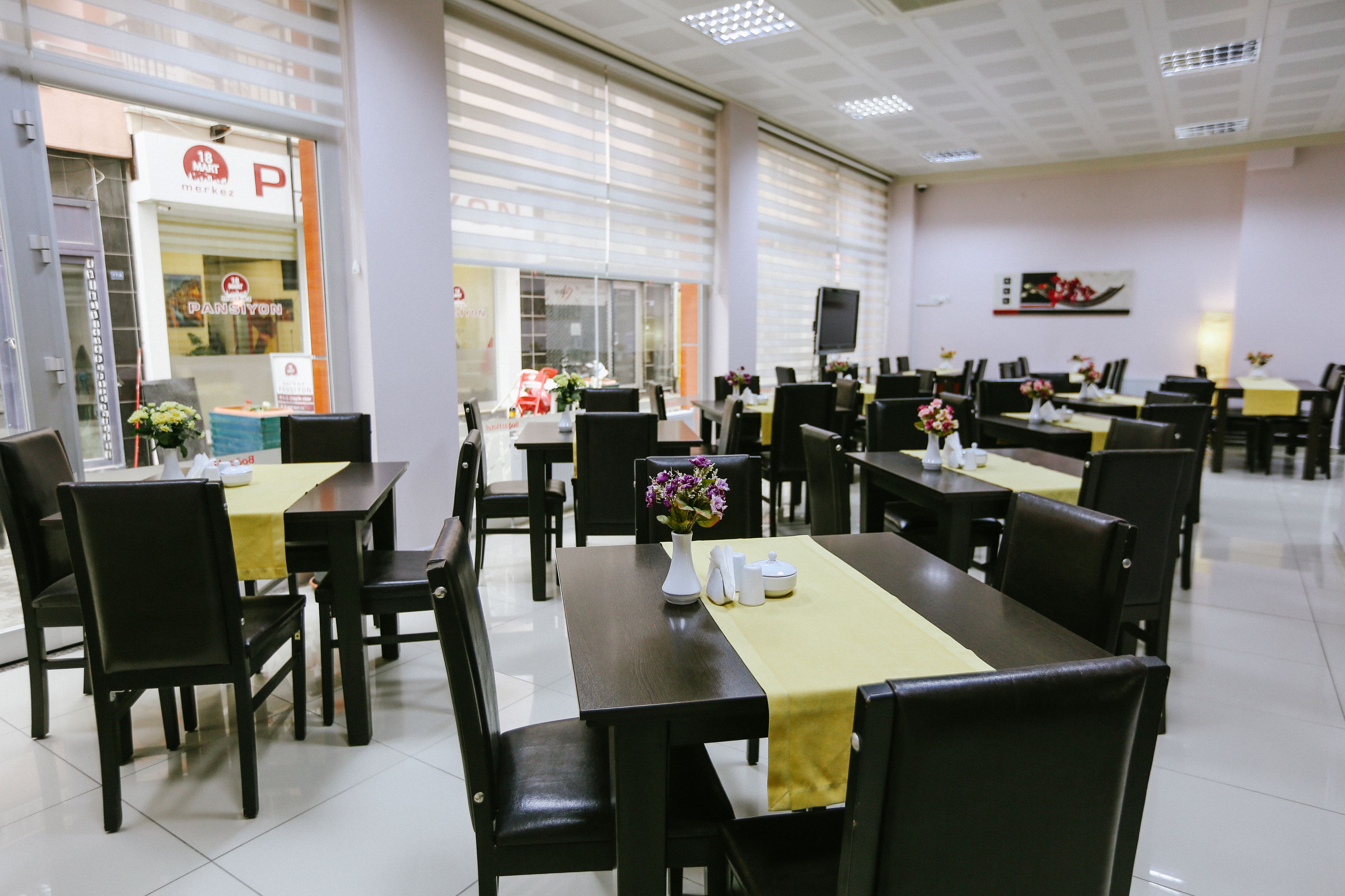 A restaurant with multiple tables and chairs, a TV mounted on the wall, and a sign indicating a parking area outside.