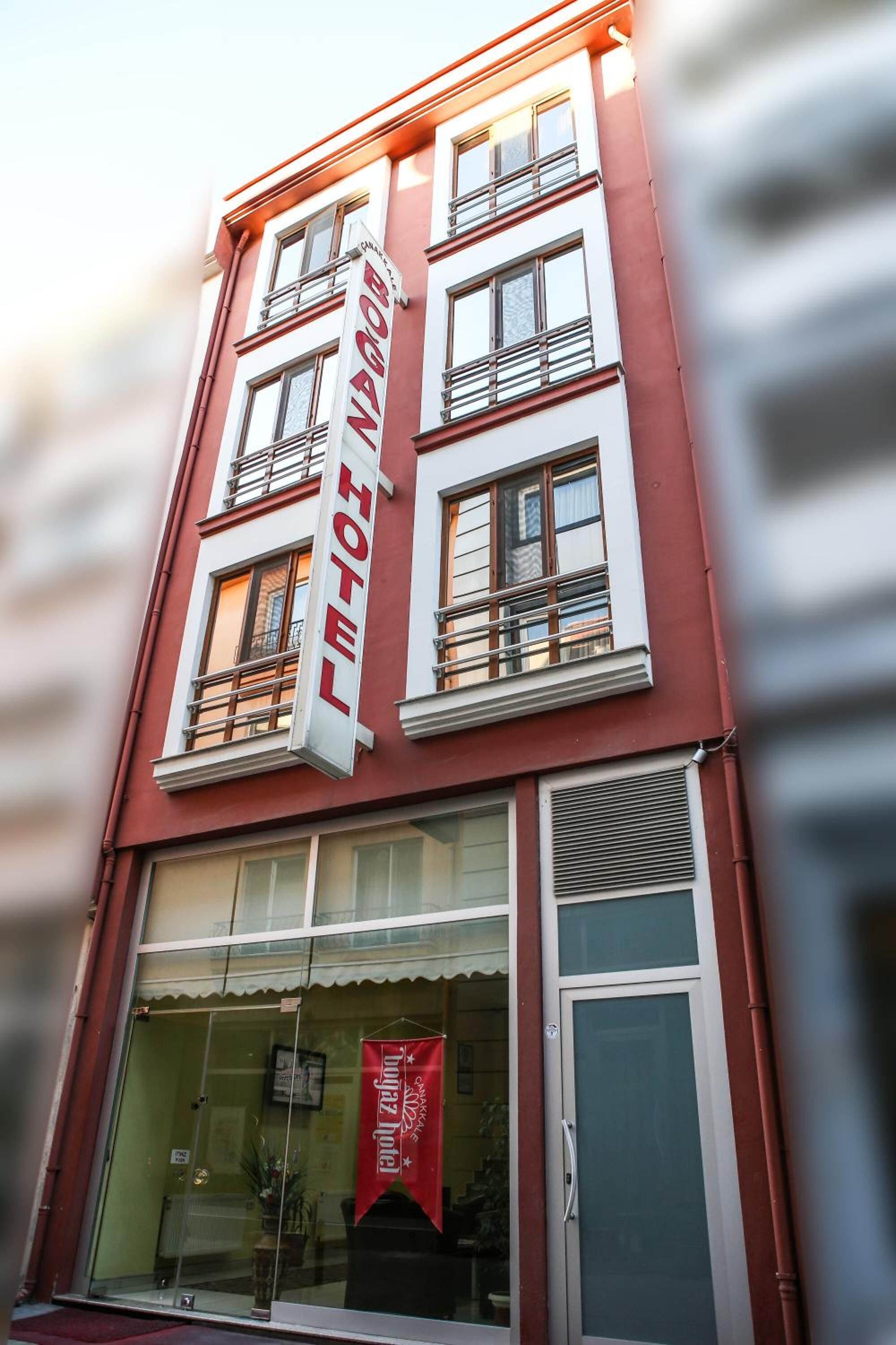 Een hotelgebouw met een rode gevel, grote ramen en een opvallend bord waarop 'HOTEL' staat.