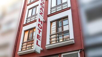Een hotelgebouw met een rode gevel, grote ramen en een opvallend bord waarop 'HOTEL' staat.