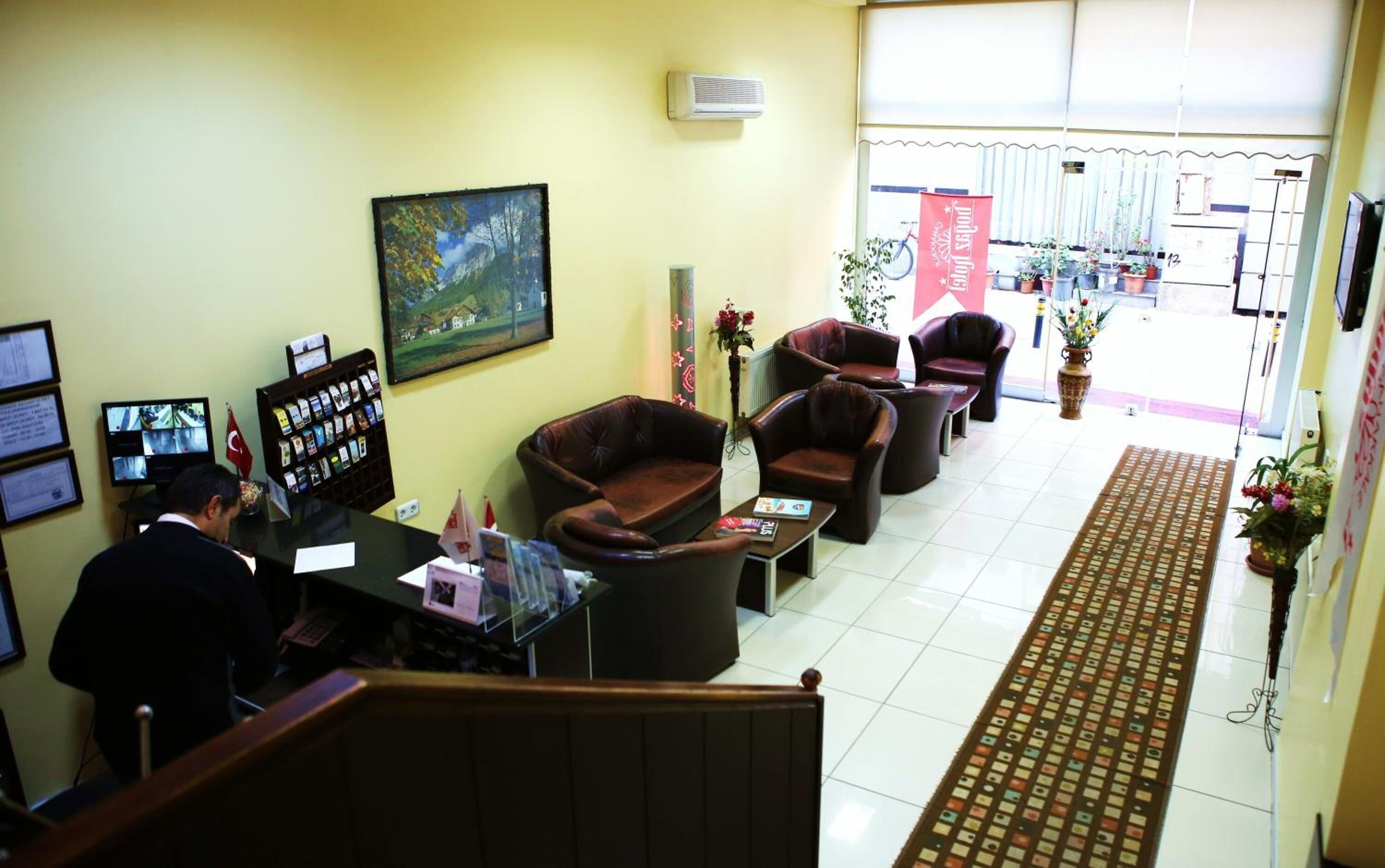 A reception area with a desk, chairs, a painting, and a view of the outside.