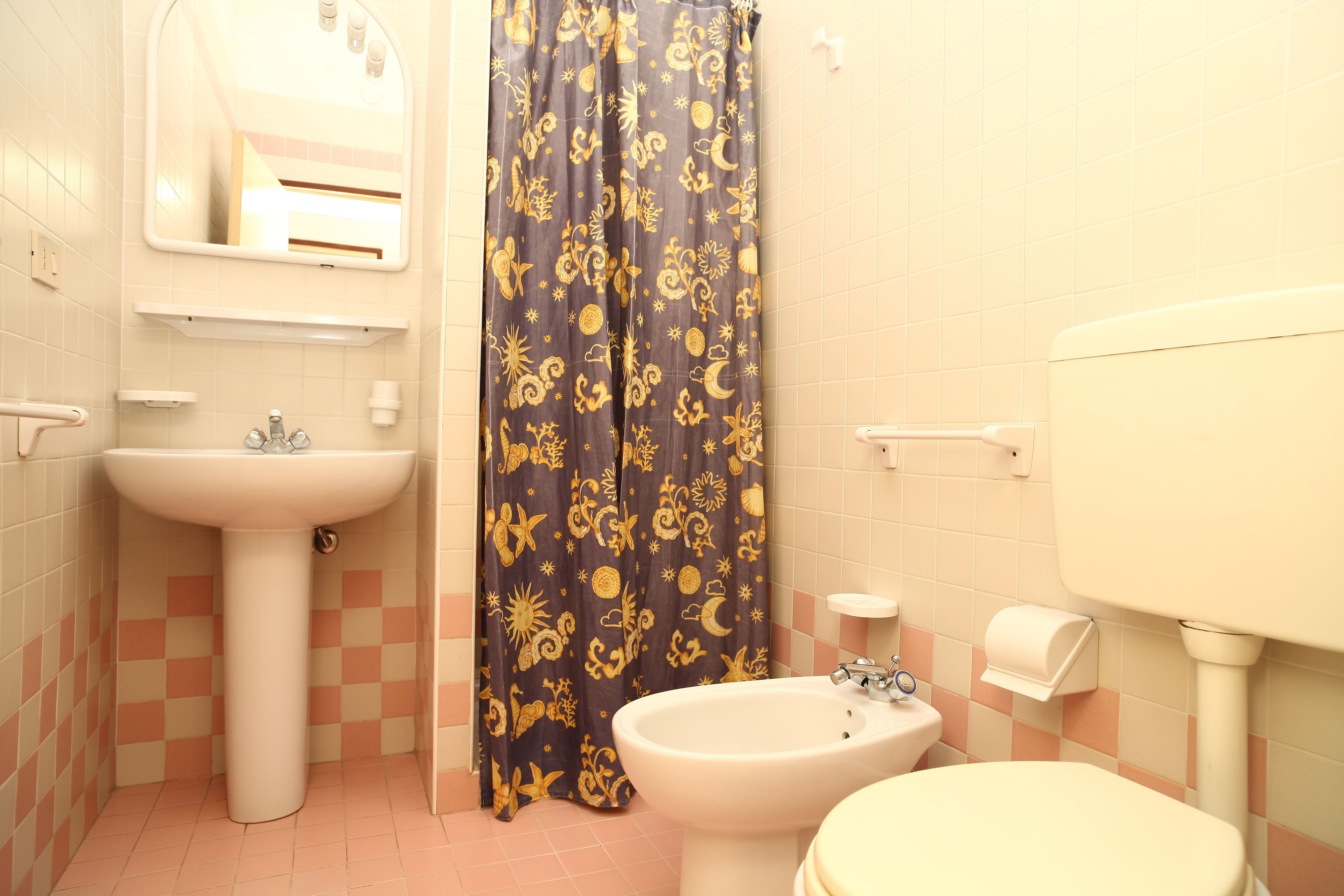 Ein Badezimmer mit Waschbecken, Bidet, Toilette und einer Duschkabine mit Blumenmuster.