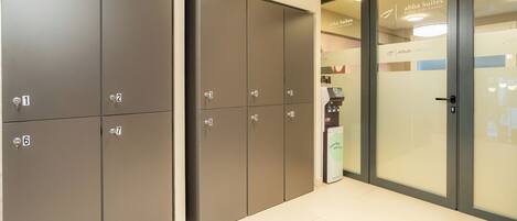 A hotel corridor with numbered lockers, a glass door entrance, and a sign for 'Abba Suites'.