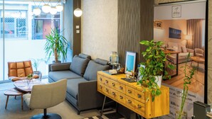A modern hotel lobby with a sofa, armchairs, a wooden sideboard, and a large window offering a view of the outside. - Bilbao City Center by abba Suites (Bilbao)