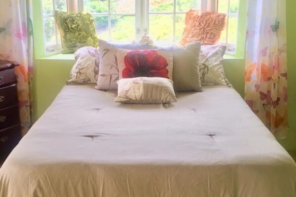 A bed with a white bedspread and multiple pillows in various colors.