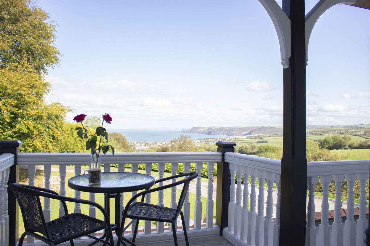 A balcony with a white railing, a round table, and two chairs.