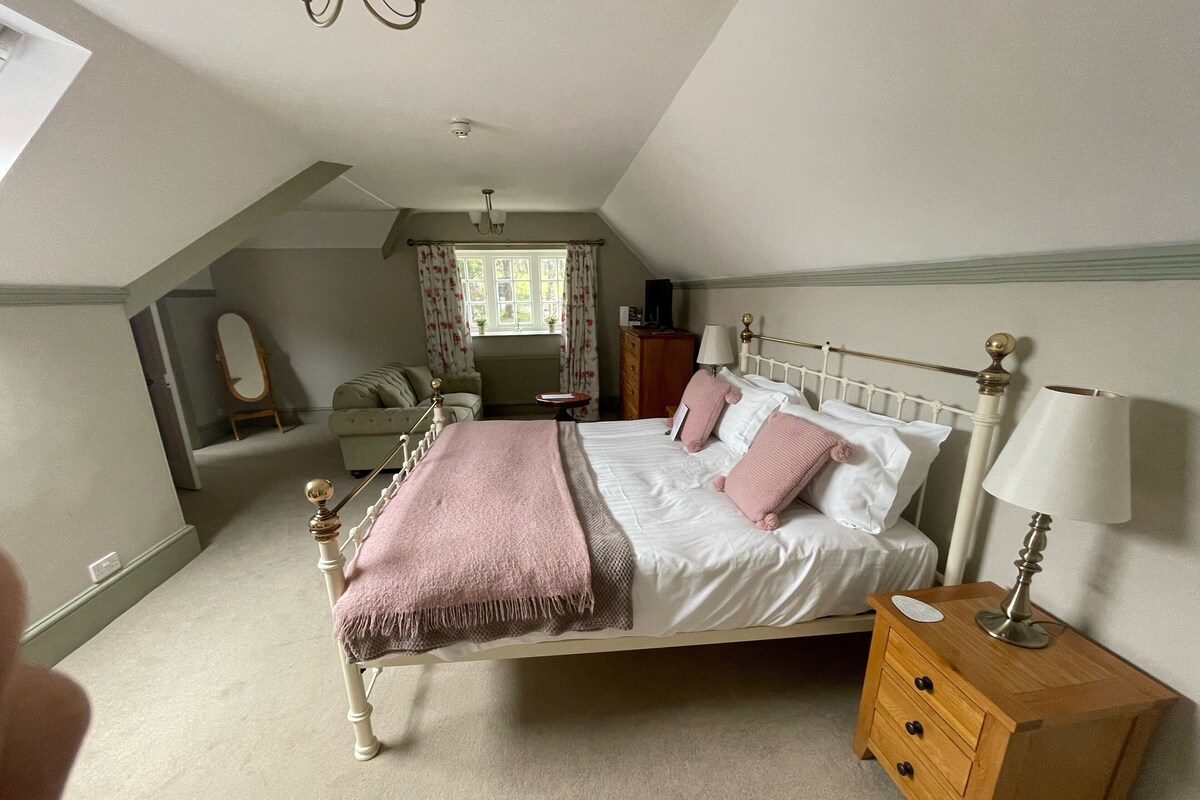 A bedroom with a bed, bedside table, dresser, and a window with curtains.