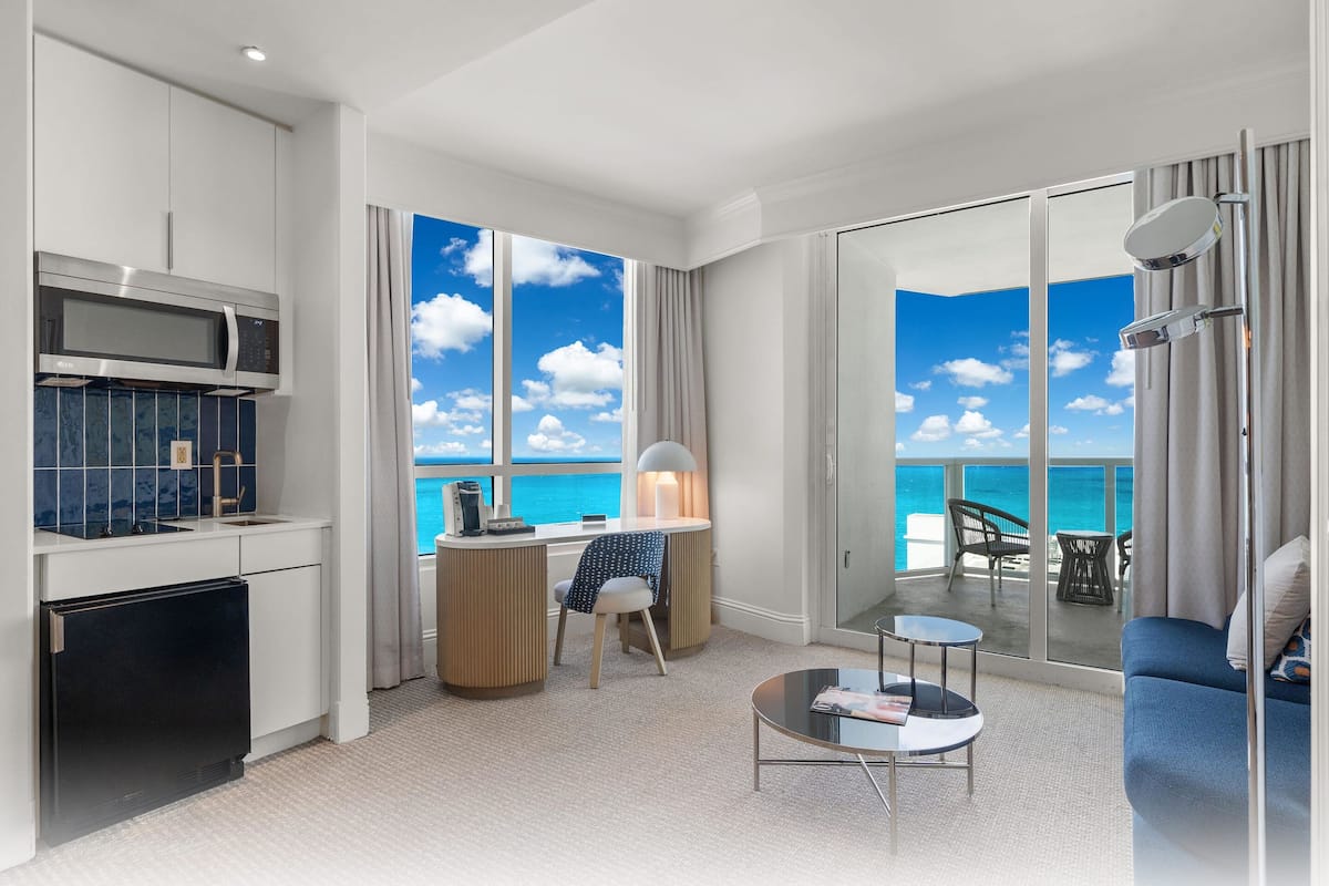 Een moderne hotelkamer met een keuken, zithoek en balkon met uitzicht op zee.