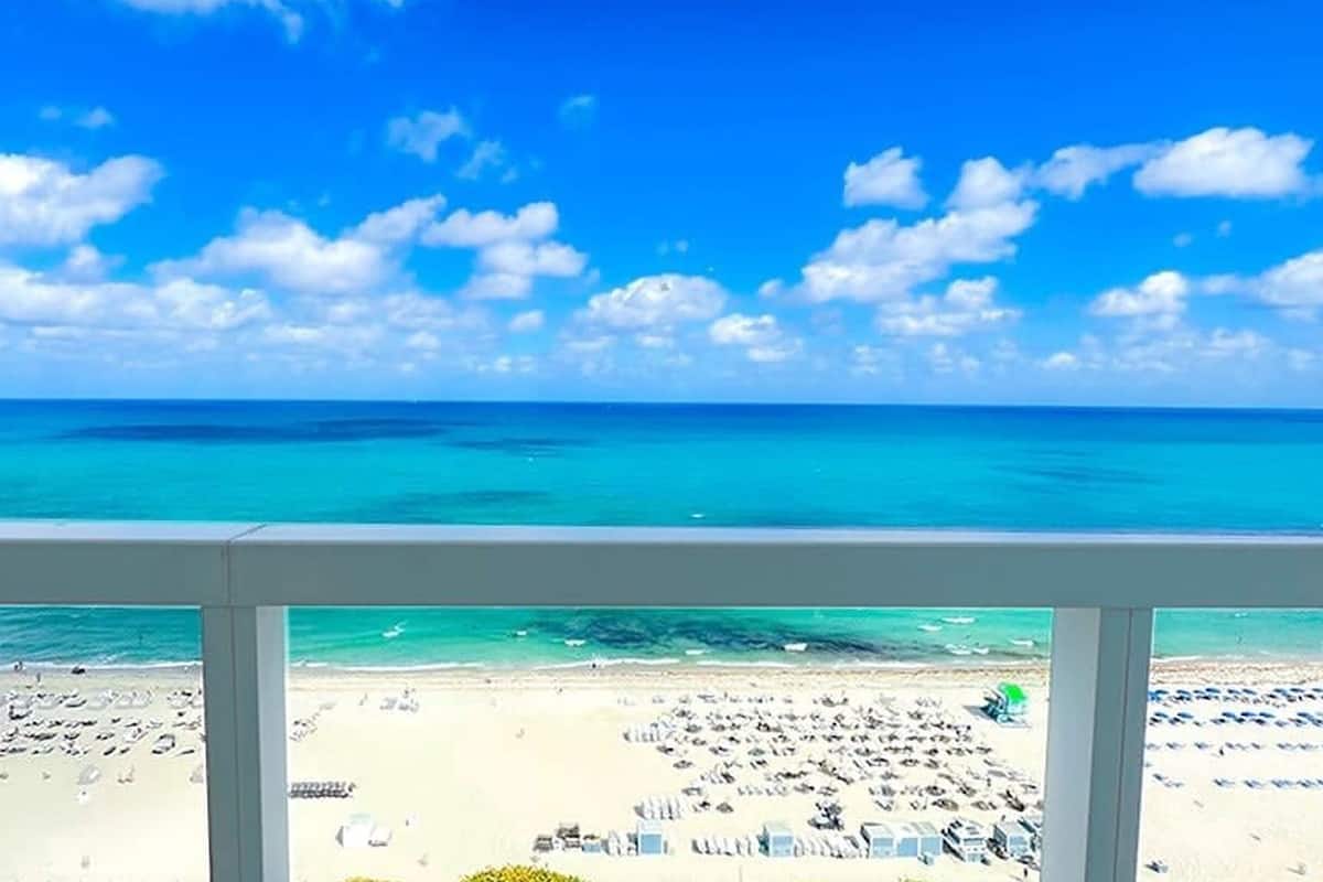 Uitzicht op een strand met heldere lucht, turquoise zee en een zandstrand met parasols en ligbedden.