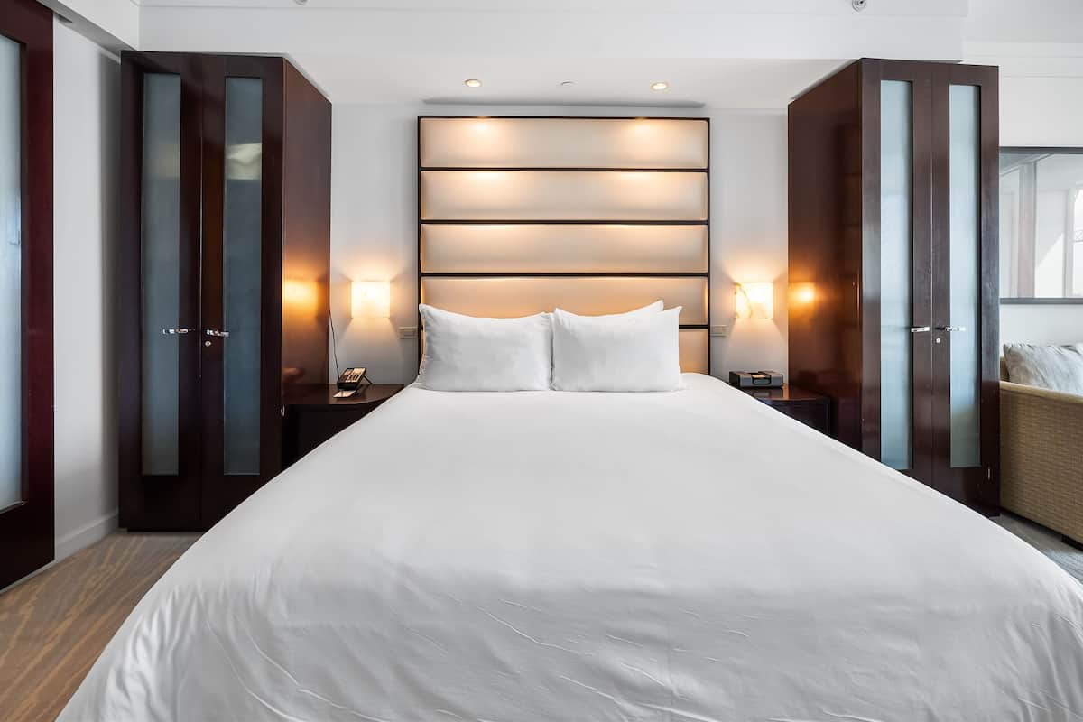 Een moderne hotelkamer met een groot bed, een donkere houten garderobe en wandlampen.