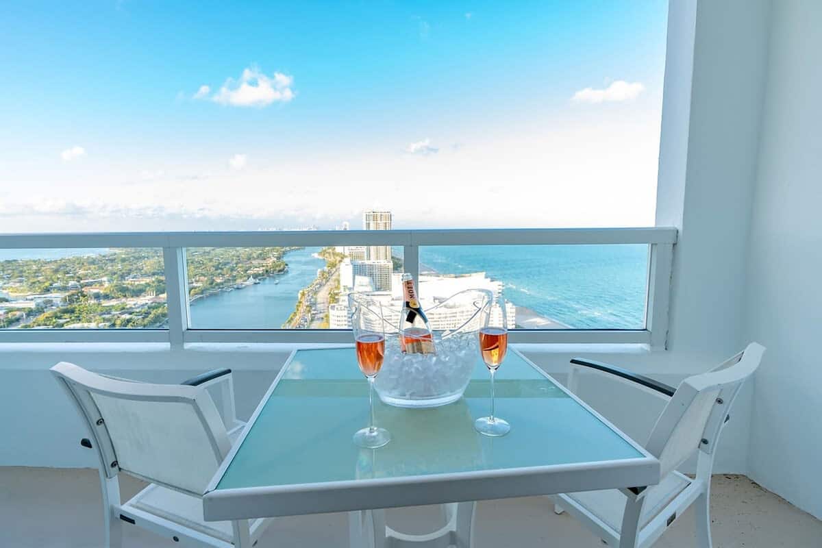 Een balkon met een tafel, twee stoelen en een champagnefles met glazen.