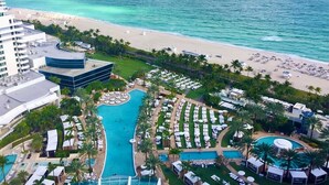 Een resort met een centraal gelegen zwembad, diverse loungegedeeltes en een strand.